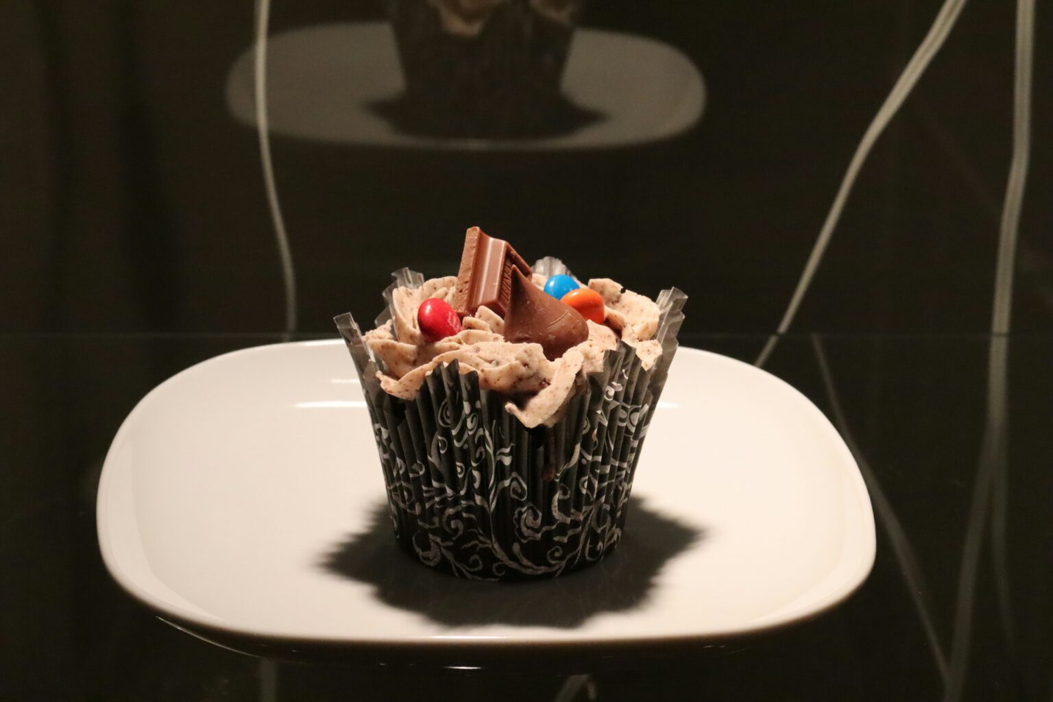 Cupcake intenso de chocolate con topping de crema, chips y barritas crujientes